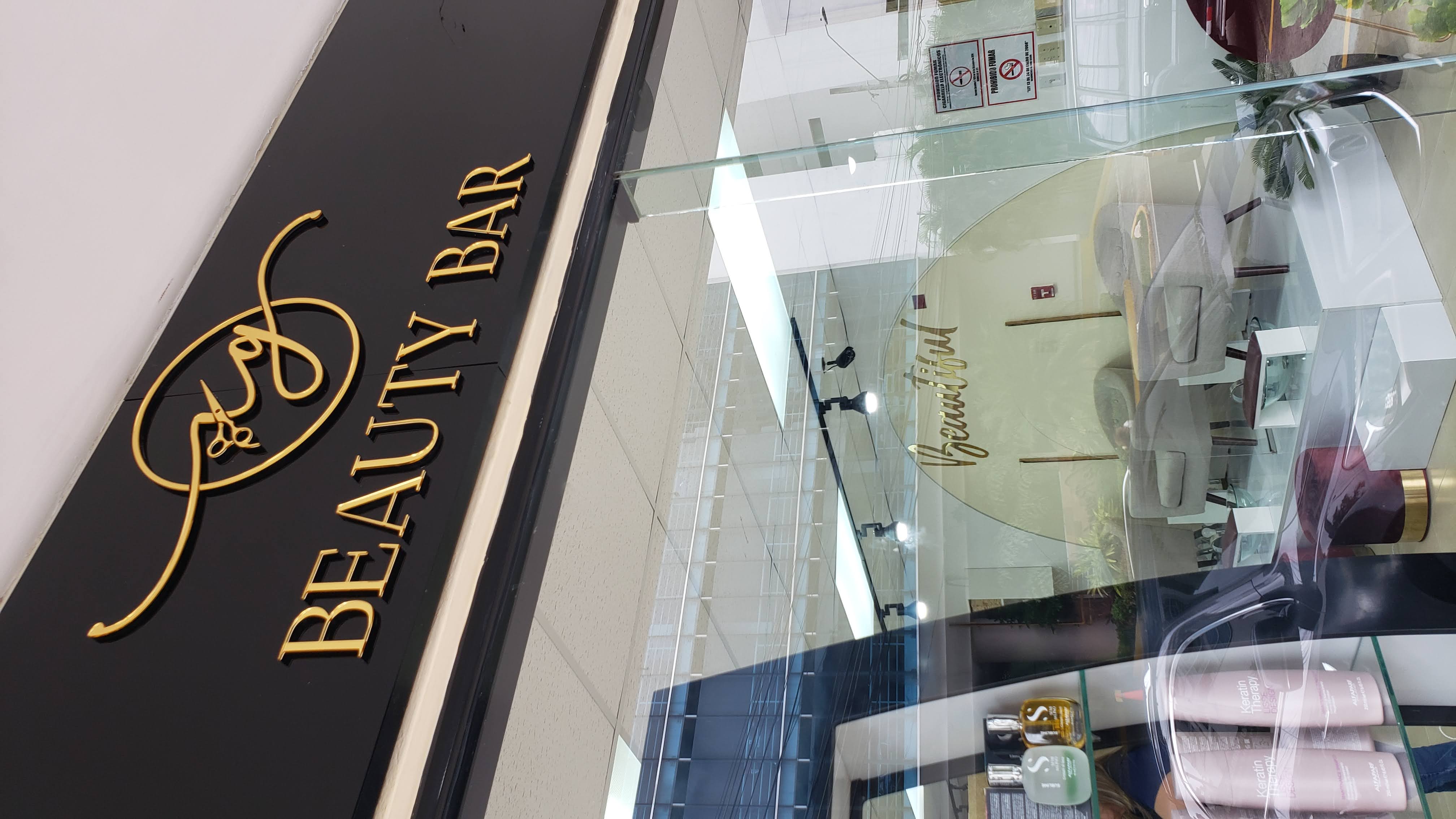 Letrero de fachada Beauty Bar en acrílico negro con letras doradas